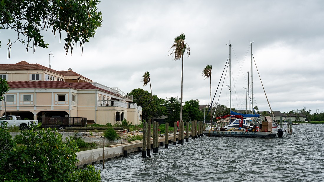 Workers install boat slips behind the vacant lot where the Buccaneer Restaurant is planned. Additional slips will be installed behind the Harbor Square office building pictured left.