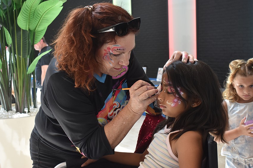 Strictly Entertainment's Wyndy Olson adds color and sparkle to the face of Lakewood Ranch 8-year-old Arya Babaria at the Back to School Bash.