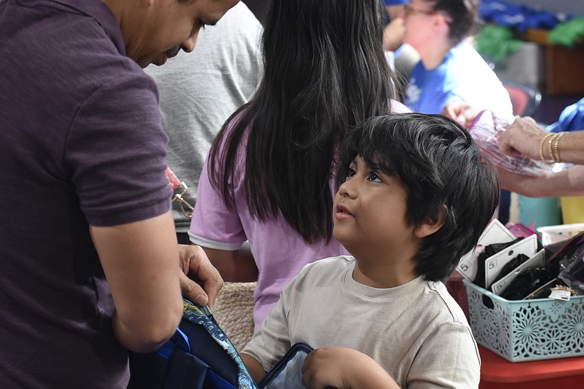 Humberto Landeros-Salazar and his son Leroy Landeros, 6, place some materials inside of a new backpack.