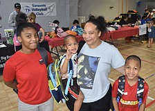 Myracle Green, 13, her brother Prince Bell, 3, mother Chavon Williams and brother King Bell, 8, leave the tables with new backpacks.