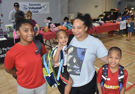 Myracle Green, 13, her brother Prince Bell, 3, mother Chavon Williams and brother King Bell, 8, leave the tables with new backpacks.