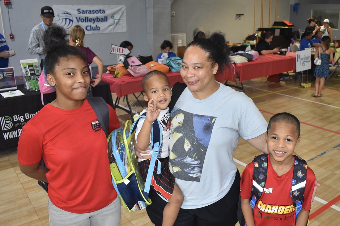 Myracle Green, 13, her brother Prince Bell, 3, mother Chavon Williams and brother King Bell, 8, leave the tables with new backpacks.