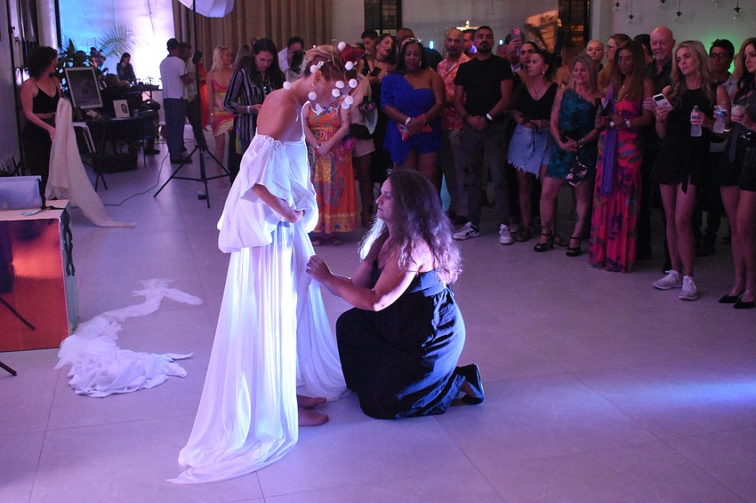 Sarasota's Yuliya Suvalava, a living sculpture, stands in front of a crowd as Sarasota's Natalia Logvinova paints her garments.