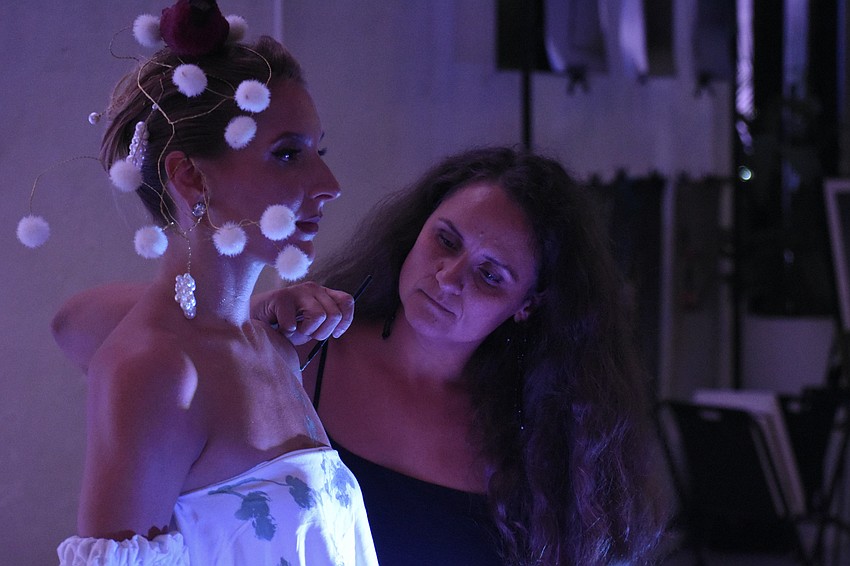 Sarasota's Yuliya Suvalava, a living sculpture, stands still as Sarasota's Natalia Logvinova paints her garments.
