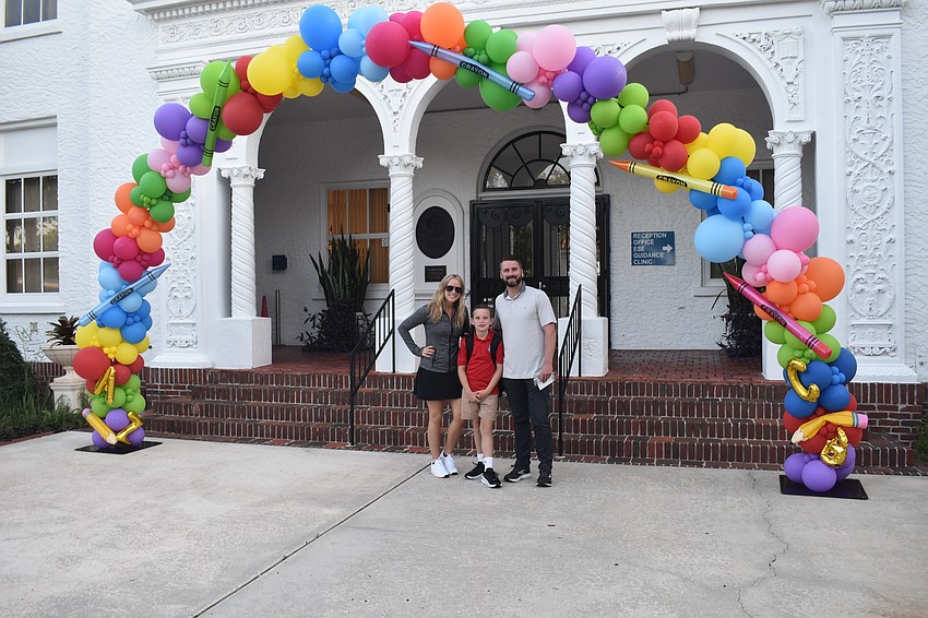 Fourth grader Henry Showalter (center) stands under the welcome archway at Southside Elementary with his parents Laurel Stevens and Colin Showalter.