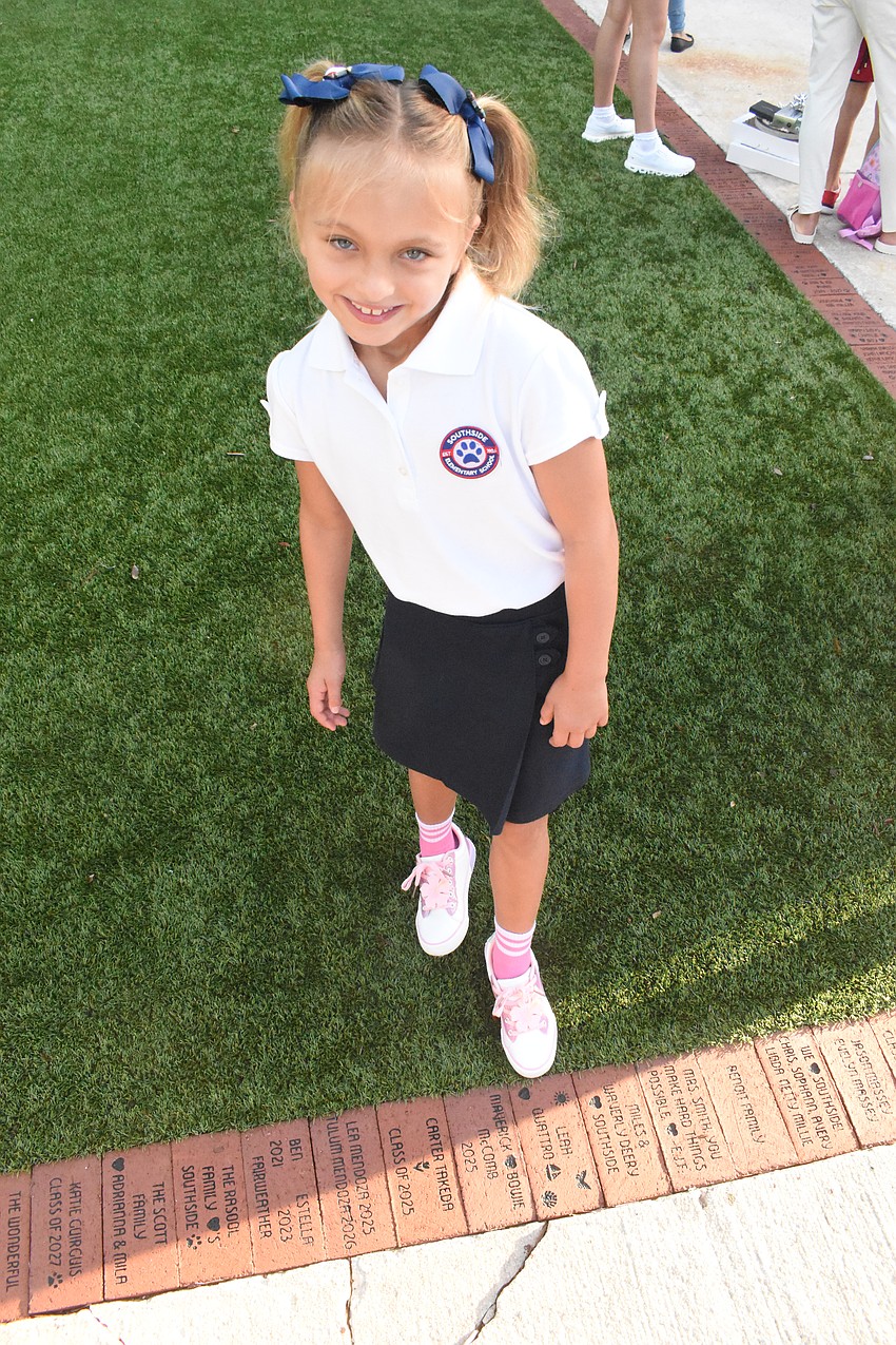 Third grader Leah Quattro points out a brick on the sidewalk with her name.