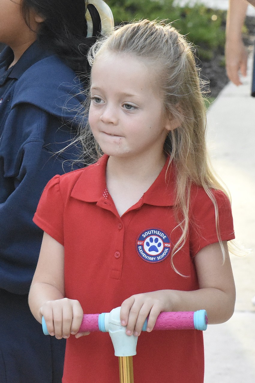 Kindergartener Vivienne Forth approaches the school building by scooter.