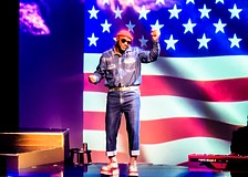 Westcoast Black Theatre Troupe's Sheldon Rhoden stands in front of an image of the American flag as he sings Marvin Gaye's rendition of "The Star Spangled Banner."