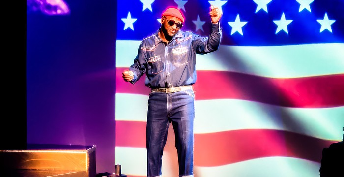 Westcoast Black Theatre Troupe's Sheldon Rhoden stands in front of an image of the American flag as he sings Marvin Gaye's rendition of "The Star Spangled Banner."