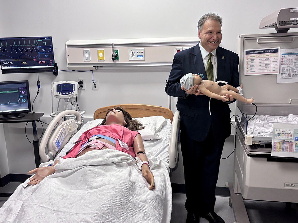 USF President Moez Limayem holds a robotic baby inside a simulation lab where nursing students will practice labor and delivery on an obstetric training mannequin.